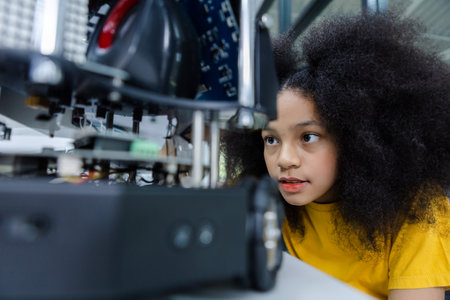 Girl with afro hairstyle wear yellow T-shirt engineer with robot for education on table at class room. Robotics learning innovation. electric system skill training. STEM education concept.の写真素材