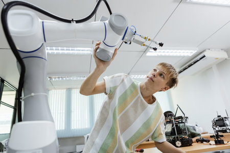 Boy caucasian education electronic robotic arm on table at class room. learning innovation robot electronic for future AI. System skill training. STEM education concept.の写真素材