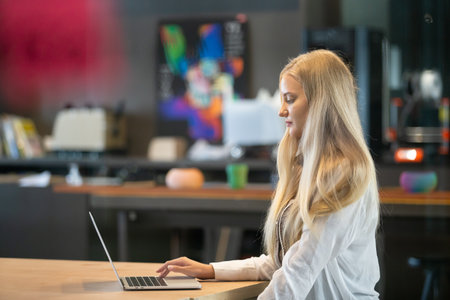 Beautiful woman with blond hair using with computer laptop at office table. professional freelancer...
