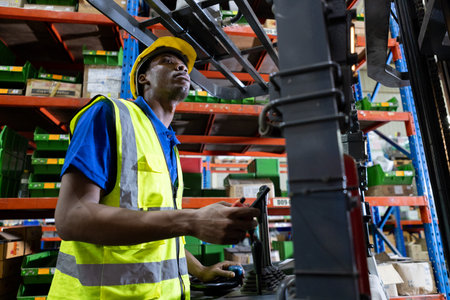 Man african american wear safety helmet driver forklift warehouse in factory. Male worker industrial...