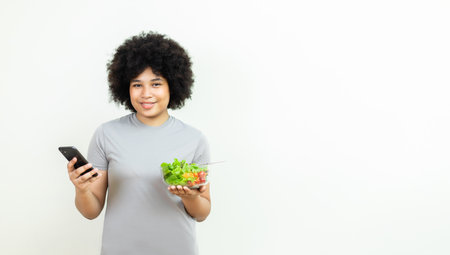 woman hair afro or fluffy using smartphone and holding salad vegetables. Female and healthy food diet. Want to lose weight. Eat healthy diet. Choose vegetable salad menu. Food full of benefits.の写真素材