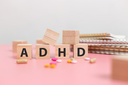 wood cube block Abbreviation of ADHD with Stethoscope and pills on pink table. Attention Deficit Hyperactivity Disorder. ADHD concept.の写真素材