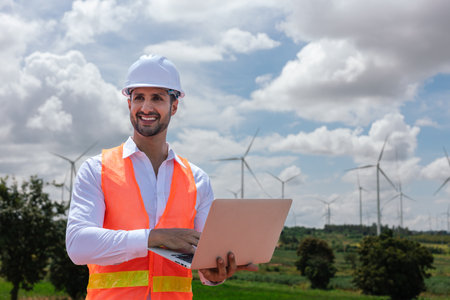 Engineer wearing safety uniform holding laptop discussed plan about renewable energy at station energy power wind. technology protect environment reduce global warming problems.の写真素材