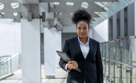 Successful young businesswoman african american black suit holding laptop smiling looking at camera at Office building. business student girl lifestyle. New generation business concept.の写真素材