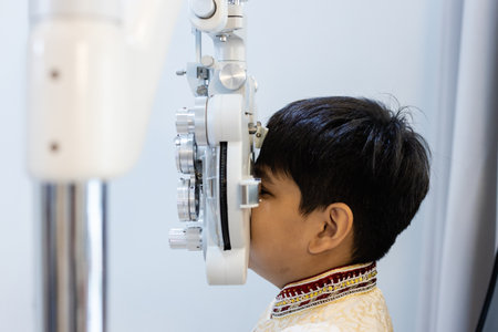 Close up asian Little boy eye exam with diagnostic ophthalmology in optical clinic. professional ophthalmic checking vision of patient. phoropter machine, ophthalmology concept.の写真素材