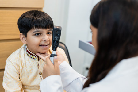 Indian child boy with women eye specialist examining eyesight modern ophthalmology equipment in clinic. Patient kid male checkup iris examines ophthalmological hospital. measure eyeglasses.の写真素材