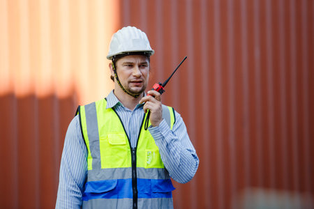 Foreman using radio walkie talkie control loading containers box in cargo for import export, Professional engineer work checking loading containers box.の写真素材