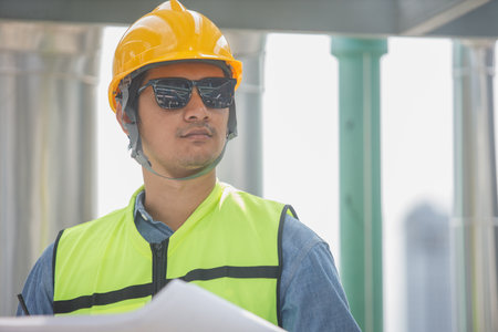 Male operator worker reading blueprint checking drawing plan cooling air piping HVAC system at industrial building. Man engineer working on Heating Ventilation and Air conditioning system.の写真素材