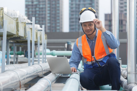 Man Industrial engineer using laptop working at rooftop construction. Male technician working...