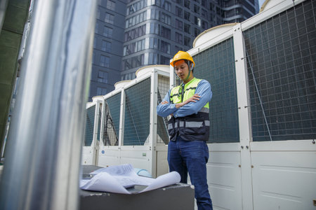 Male operator worker reading blueprint checking drawing plan cooling air piping HVAC system at industrial building. Man engineer working on Heating Ventilation and Air conditioning system.の写真素材