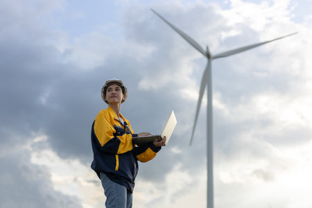 Renewable energy systems concept, engineer female using laptop working wind turbine for alternative energy, Technology protect environment reduce global warming problems.の写真素材