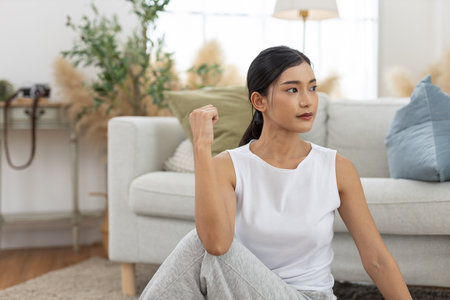 young asian female twist body stretching practicing yoga sitting on floor in living room at home. Relax and stretch and workout morning at home. Activity body movement exercises.の写真素材