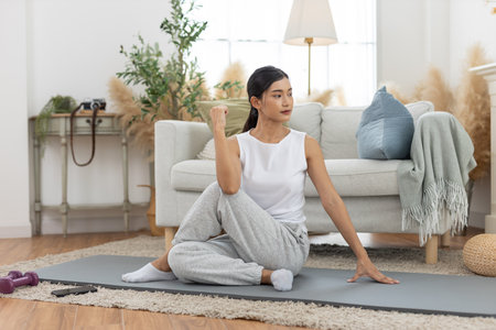 young asian female twist body stretching practicing yoga sitting on floor in living room at home....