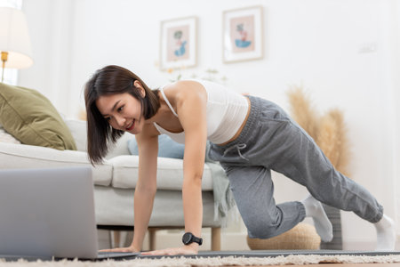 young asian female arm shoulder stretching practicing yoga with laptop sitting on floor in living room at home. Relax and stretch and workout morning at home. Activity body movement exercises.の写真素材