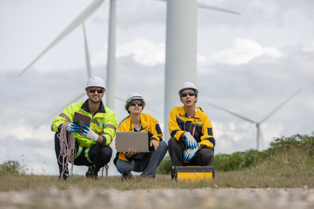 Engineer wearing safety uniform using laptop discussed plan about renewable energy at station energy power wind turbine. technology protect environment reduce global warming problems.の写真素材