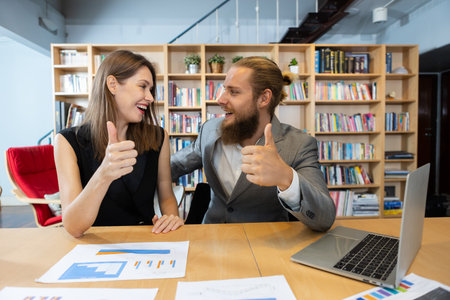 Two businesspeople looking at camera and thumb up with laptop. Teamwork planning make branding. strategy marketing of company. woman manager and creative man meeting for work in office.の写真素材