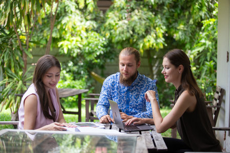 Group of business professionals analyzing colorful charts and graphs during an outdoor meeting, showcasing teamwork, data-driven decision-making, and creative corporate strategy.の写真素材