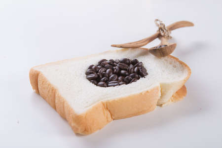 coffee Beans in hole bread on wite table Beside a wooden spoon restsの写真素材