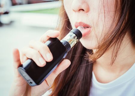Close up Mouth woman smoking e-cigarette with the smoke on the side