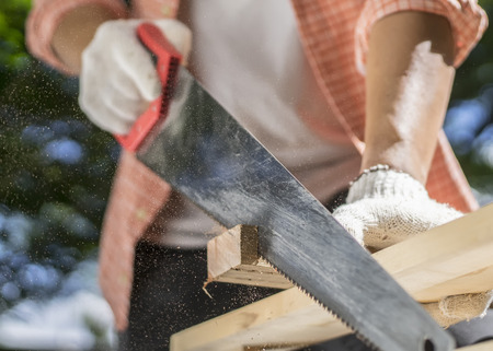 Carpenter holding a hand saw on the work benchの写真素材
