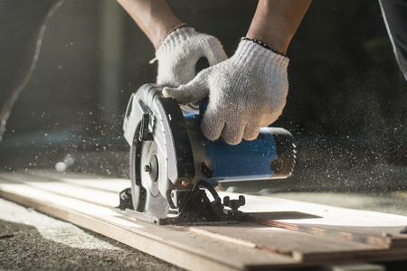 Carpenter using circular saw for cutting wooden boards.の写真素材
