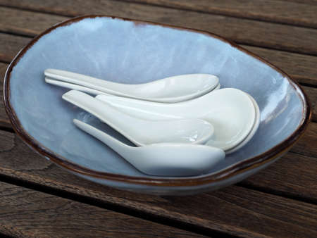 White spoons in blue plate on wood table closeupの写真素材