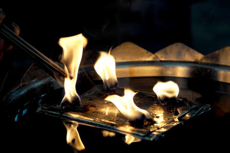 People light incense joss sticks with oil lamp at the templeの写真素材