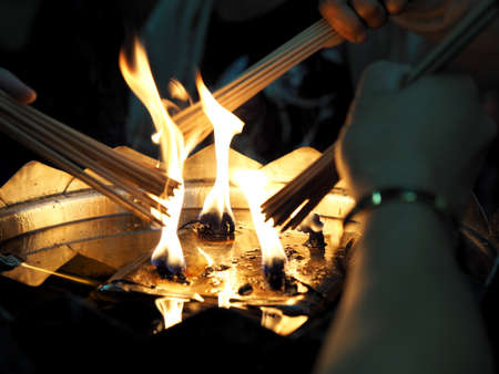 People light incense joss sticks with oil lamp at the templeの写真素材