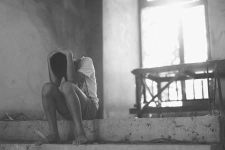 Sad boy sitting on stairs emotional stress and pain, afraid, restricted, trapped, call for help, struggle, terrified, violence, slave, Human Rights Day concept.の写真素材