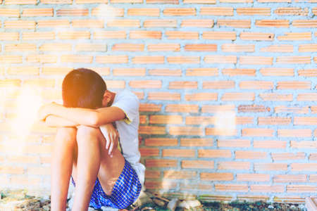 Sad, lonely, unhappy, disappointed child sitting alone emotional stress and pain, afraid, restricted, trapped, call for help, struggle, terrified, violence, slave, Human Rights Day concept.の写真素材