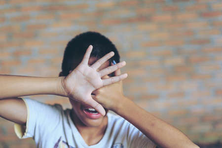 A fearful child in angle of abandoned building image blur Children violence. boy, lad with her hand extended signaling to Stop,child bondage in angle of abandoned building image blur and pain, afraid, restricted, trapped, call for help, struggle, terrifieの写真素材