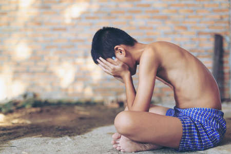 Portrait of a crying  boy, lad. She is covering her face Children violence. boy, lad with her hand extended signaling to Stop,child bondage in angle of abandoned building image blur and pain, afraid, restricted, trapped, call for help, struggle, terrifiedの写真素材