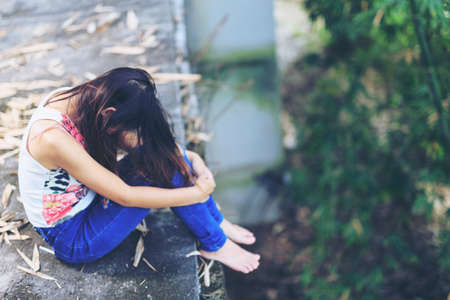 Teenager with depression sitting alone on abandoned buildingsの写真素材
