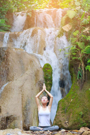Woman Yoga - relax in waterfall natureの写真素材