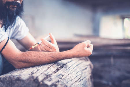 Drug addict young man with syringe in action, Drug abuse concept.,の写真素材