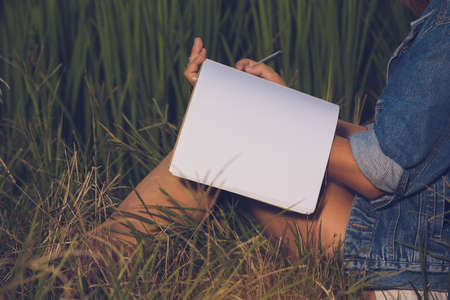 young woman standing reading book at meadows.