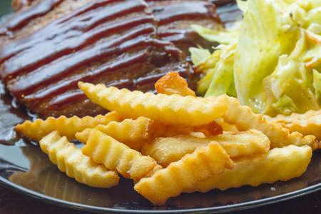 Grilled steaks, boiled French fries and vegetable saladの写真素材