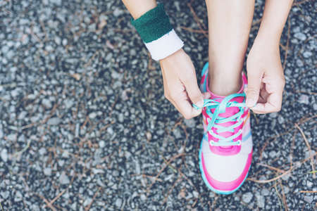 Asia woman runner jogging exercise alone to lose fat weight tying shoelacesの写真素材