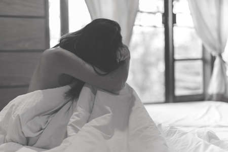 woman sit on a bed in a bedroom - concept photo of Sexual assaultの写真素材