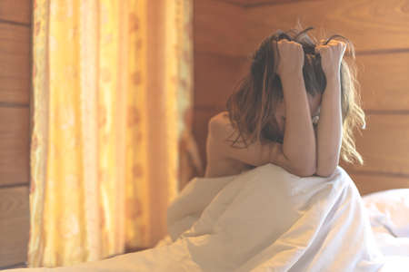 woman sit on a bed in a bedroom - concept photo of Sexual assaultの写真素材