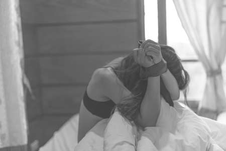 woman sit on a bed in a bedroom - concept photo of Sexual assaultの写真素材