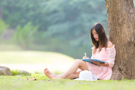 Asian girl reading a book in a meadow.の写真素材