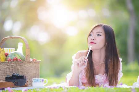 Asian girl reading a book in a meadow.の写真素材