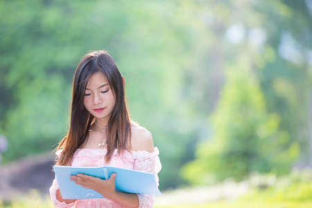 Asian girl reading a book in a meadow.の写真素材