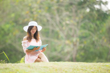 Asian girl reading a book in a meadow.の写真素材