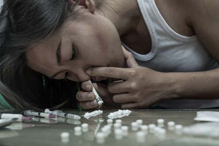 Drug addict young woman with syringe in action, Drug abuse concept.の写真素材