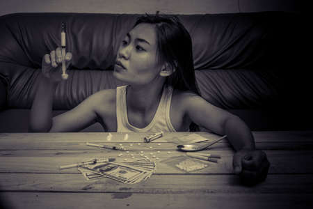 Drug addict young woman with syringe in action, Drug abuse concept.の写真素材