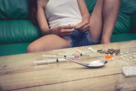 Drug addict young woman with syringe in action, Drug abuse concept.の写真素材