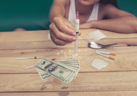 Drug addict young woman with syringe in action, Drug abuse concept.の写真素材