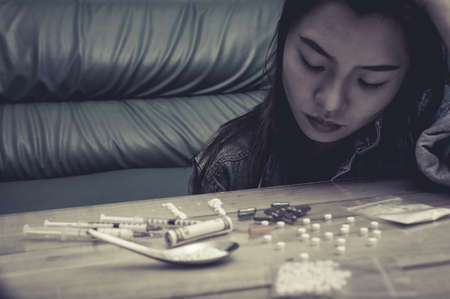 Drug addict young woman with syringe in action, Drug abuse concept.の写真素材